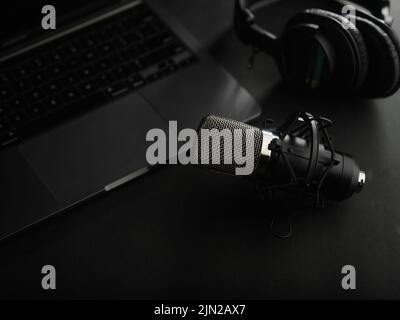 Heimbüro. Studiomikrofon und Studiokopfhörer auf einem Laptop auf grauem Hintergrund. Soundarbeit, Podcast, Radio, Journalismus, Bloggen, Streaming, ra Stockfoto