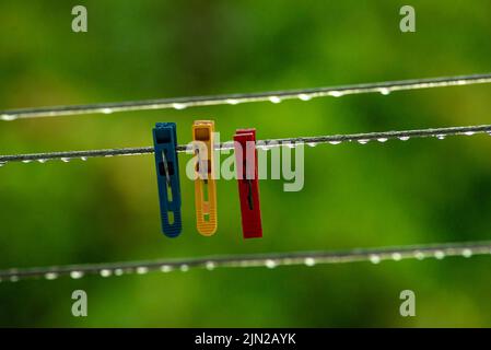 Die Kleidungslinien einer Kleidung drehen sich mit vielen Regentropfen an der Schnur vor einem dunklen Hintergrund, nach dem Regen. Retro-Art, die Wäsche zu waschen. peg Stockfoto