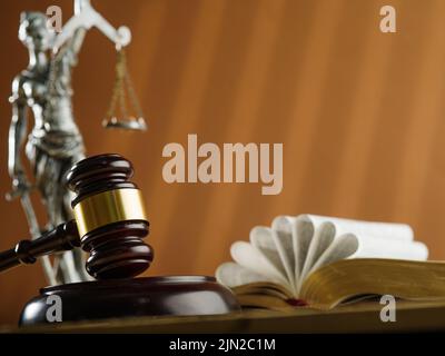 Bronzestatuette der Göttin der Gerechtigkeit - Themis, ein hölzerner Gavel eines Richters und die Verfassung auf beigem Hintergrund. Gerichtshof und Justiz, Bibel, C Stockfoto