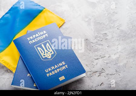 Auf einem dunklen Hintergrund zwei ukrainische biometrische Pässe vor dem Hintergrund der ukrainischen Flagge. Kampf für Freiheit, Unabhängigkeit gegen Russisch Stockfoto