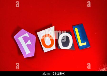 Das Wort „Fool“ mit ausgeschnittenen Papierbuchstaben in der Lösegeld-Note-Effekt-Typografie Stockfoto