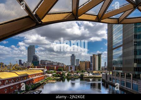 London, Großbritannien - Jun 10 2022: Blick auf die Wolkenkratzer von Canary Wharf und das North Dock, aufgenommen vom Dachgarten, umrahmt von einem wellenförmigen Dach Stockfoto