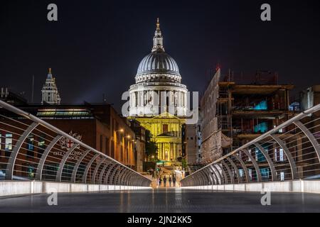 London, Großbritannien - 11. Juni 2022: Nachtansicht der Millennium Bridge und der beleuchteten St. Paul's Cathedral in London, Großbritannien Stockfoto