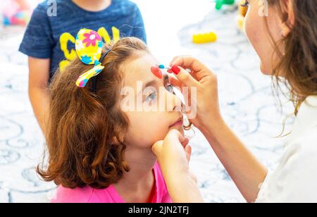 BAKU, ASERBAIDSCHAN- 13 MAY 2019 : Mädchen zeichnet kleine Mädchen Aqua Make-up. Gesichtsbemalung. Freizeit für Kinder. Stockfoto