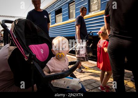 Pokrowsk, Oblast Donezk, Ukraine. 2. August 2022. Ein Baby, das im Kinderwagen sitzt, wartet auf den Evakuierungszug mit seinen Eltern am Bahnhof Pokrovsk. Inmitten der intensivierten Kämpfe im östlichen Teil der Ukraine intensiviert die Ostukraine nun ihre zivile Evakuierung, da Millionen ukrainischer Familien aus dem immer näher rückt Krieg evakuiert wurden, da viele von ihnen in den westlichen Teil des Landes verlagert werden.Laut den Vereinten Nationen werden die meisten von ihnen in den Westen des Landes umgesiedelt. Mindestens 12 Millionen Menschen sind seit dem russischen Einmarsch in die Ukraine aus ihren Häusern geflohen, während sieben Millionen Menschen sind Stockfoto