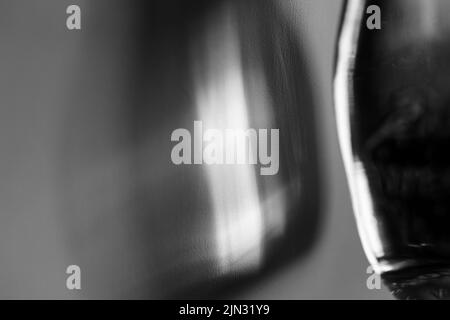 Glasflasche wirft einen schönen Schatten und ätzenden Effekt, wenn Licht durch ein Glas geht. Schwarzweiß-Foto. Abstrakter Hintergrund Stockfoto