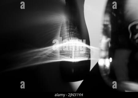 Glasflasche wirft einen schönen Schatten und ätzenden Effekt, wenn Licht durch ein Glas geht. Schwarzweiß-Foto. Abstrakter Hintergrund Stockfoto