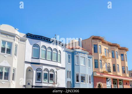 Dreistöckige Häuser mit Geländern am Eingang und Wohnung über einem Geschäft in San Francisco, CA. Es gibt Häuser von links neben einer Wohnung Stockfoto