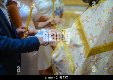 Blick auf eine Hochzeit in der Oortodoxer Kirche, brennende Kerzen im Tempel, die Heilige bibel, Schrift für das Sakrament, orthodoxes Objekt, orthodoxes Kreuz in der Kirche, Stockfoto