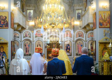 Blick auf eine Hochzeit in der Oortodoxer Kirche, brennende Kerzen im Tempel, die Heilige bibel, Schrift für das Sakrament, orthodoxes Objekt, orthodoxes Kreuz in der Kirche, Stockfoto