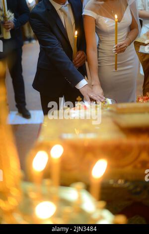 Blick auf eine Hochzeit in der Oortodoxer Kirche, brennende Kerzen im Tempel, die Heilige bibel, Schrift für das Sakrament, orthodoxes Objekt, orthodoxes Kreuz in der Kirche, Stockfoto