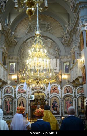 Blick auf eine Hochzeit in der Oortodoxer Kirche, brennende Kerzen im Tempel, die Heilige bibel, Schrift für das Sakrament, orthodoxes Objekt, orthodoxes Kreuz in der Kirche, Stockfoto