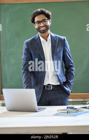 Lächelnder junger indischer Geschäftsmann in Anzug im Büro. Hochformat Stockfoto