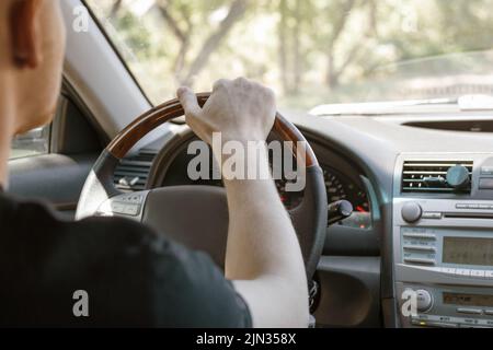 Ein Mann, der ein Auto fährt, Rückansicht aus dem Fahrgastraum. Sicheres Fahren. Stockfoto