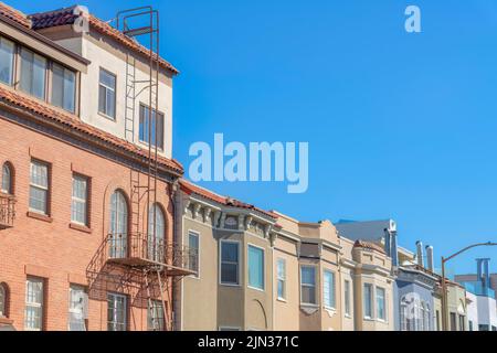 Wohnung und Gewächshäuser in einem städtischen Gebiet in San Francisco, CA. Auf der linken Seite befindet sich ein Apartmentgebäude mit Ziegelsteinen und Nottreppen Stockfoto