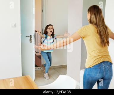 Kind Mutter Tochter Rucksack Haus Bildung Schule Familie Student willkommen Umarmung zusammen liebe Frau elementare Hause Mädchen Frau Stockfoto