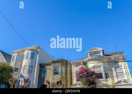 Kabelsalat gegen die Häuserzeile in San Francisco, CA. Drei Gebäude mit grauem Haus in der Mitte der Wohnung auf der linken Seite ein Stockfoto