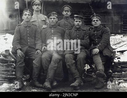 Eine informelle Gruppe deutscher Soldaten, die während des Ersten Weltkriegs zusammen mit Schnee hinter ihnen sitzen. Einschließlich der Empfänger des Eisenkreuzes. Stockfoto