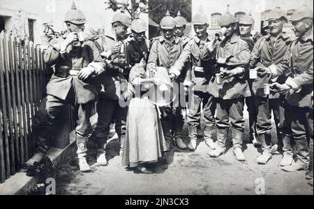 Anfang des Ersten Weltkriegs Gruppe deutscher Soldaten, die Erfrischungen von einer kleinen Frau mit einem großen Krug um 1914 nahmen Stockfoto