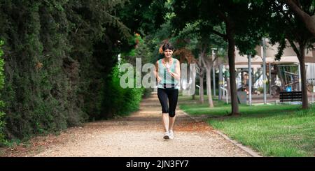 Frau mittleren Alters, die im Sommer morgens im Park läuft Stockfoto