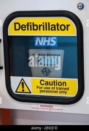 London, Vereinigtes Königreich - 05. Februar 2019: Hellgelbes Warnschild auf der automatisierten externen Defibrillatorbox, die in der Nähe an der Wand des Einkaufszentrums angebracht ist Stockfoto