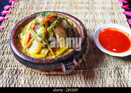 Tajine oder Tagine: Traditionelle berberische Gerichte, die in einer Steingutschüssel in einem typisch marokkanischen Straßenrestaurant serviert werden, Nahaufnahme Stockfoto