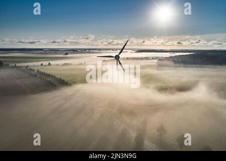 Onshore-Windturbine, die in der Morgensonne im Nebel steht Stockfoto