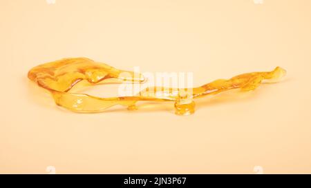 Piace golden dab Konzentrat aus Cannabiswachs Nahaufnahme auf gelbem Hintergrund, Marihuanaharz. Stockfoto