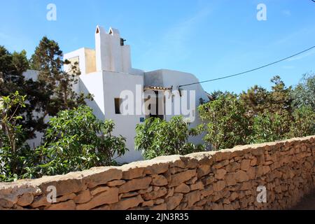 Schönes quadratisches typisches, traditionelles ibizisches pitiusa weißes Haus mit einem sehr milden Klima, lokaler Vegetation und Steinmauern in formentera Stockfoto