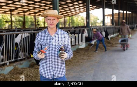 Landwirt mit Spritze und Medizin in den Händen auf dem Milchviehbetrieb Stockfoto