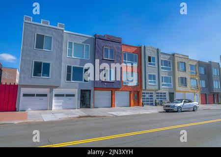 Stadthäuser mit angebundenen zwei-Auto-Garagen an der Straße in San Francisco, CA. Es gibt eine Straße vorne mit einem Auto, das vor dem Driv geparkt ist Stockfoto