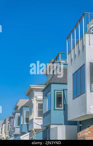 Seitenansicht einer Häuserzeile mit hervorstehenden Fenstern zum Himmel in San Francisco, CA. Es gibt zwei Häuser an der Vorderseite mit Geländern auf Dachdecks Stockfoto