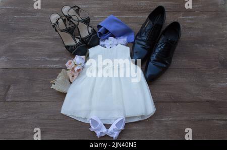 Bild von einem Baby Mädchen Taufkleid mit einem Paar Männer und Frauen Schuhe. Hinweis auf das glückliche Ereignis einer Geburt Stockfoto