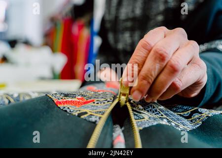 Die Designerin zippte den Reißverschluss, den sie gerade genäht hatte. Stockfoto