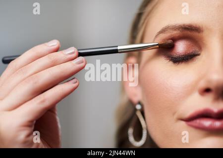 Denn das Auge muss auffallen. Nahaufnahme einer schönen jungen Braut, die sich schminke, während sie sich in ihrer Garderobe auf ihre Hochzeit vorbereitete. Stockfoto