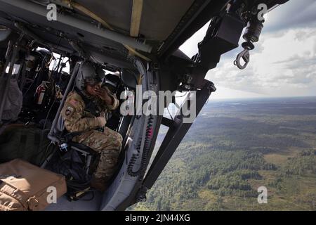 Ein Soldat der US-Armee, der dem 1-230. Assault Helicopter Bataillon, Tennessee Army National Guard, zugewiesen wurde, kommuniziert mit seiner UH-60 Blackhawk-Flugcrew während der Vorverfallsplanprobe für Northern Strike 22 oberhalb von Camp Grayling, mich., 6. August 2022. Northern Strike wurde entwickelt, um 7.400 Service-Mitglieder mit verschiedenen Schulungsformen herauszufordern, die die Interoperabilität zwischen mehreren Komponenten, multinationalen und behördenübergreifenden Partnern fördern. Stockfoto