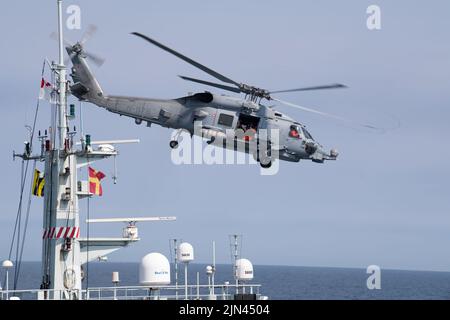 Ein an HDMS Triton angeschlossener Hubschrauber der Royal Danish Navy MH-60R fliegt während der Operation Nanook, Northern Atlantic Ocean, am 5. August 2022 über dem Mast des Royal Canadian Navy Vessel HMCS Goose Bay. Die Operation Nanook ist eine multinationale militärische Übung, die die Fähigkeiten der Vereinigten Staaten und der Partnerländer hervorhebt, gemeinsame maritime Ziele voranzubringen. (USA Foto der Küstenwache von Petty Officer, Klasse 3., Matthew Abban) Stockfoto