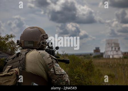 Ein Betreiber der 20. Special Forces Group unterstützt ein Angriffsteam bei der Räumung eines simulierten gegnerischen Geländes während einer Live-Feuerübung in der Nähe von Chester Township, Michigan, am 6. August 2022. Die Mission war Teil von Northern Strike, einer jährlichen multinationalen gemeinsamen Trainingsveranstaltung mit Sitz im Camp Greyling Joint Maneuver Training Center in Michigan. (USA Foto der Armee-Nationalgarde von SPC. Cody Muzio.) Stockfoto