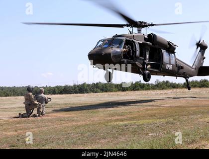 CAMP BONDSTEEL, Kosovo – Flieger der US-Armee aus dem Bataillon 2., 224. Aviation Regiment, 29. Combat Aviation Brigade, 29. Infantry Division, Virginia National Guard, führen im Camp Bondsteel, Kosovo, am 8. August 2022 eine Schlingentraining für nicht-Flugsoldaten durch. Die Soldaten des Liaison Monitoring Teams des Regionalkommandos Ost der Kosovo-Streitkräfte unternahmen die Schulung, um zu lernen, wie sie sicher Schleuderlasten durchführen können, was das schnelle Einsetzen von Vorräten und Ausrüstung selbst an den entlegensten Orten ermöglicht. (USA Armeefoto von Sgt. 1. Klasse Warren W. Wright Jr., 138. Public Affairs Stockfoto