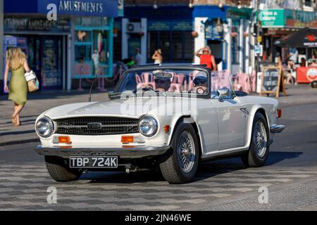 Ein weißes Triumph TR6 Cabriolet mit Kapuze wird während der Hitzewelle von 2022 entlang der Marine Parade an der englischen Küste in Essex gefahren Stockfoto