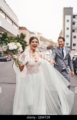 Die Braut läuft mit ihrem Bräutigam davon. Ein schönes Paar ist am Hochzeitstag in der Stadt. Stockfoto