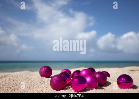 Rosa Weihnachtskugeln am Strand. Weihnachten in den Tropen. Selektiver Fokus Stockfoto