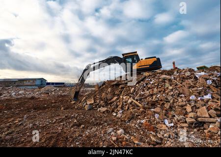 Bagger schüttet Erde auf Müllhaufen an der Abbruchstelle Stockfoto