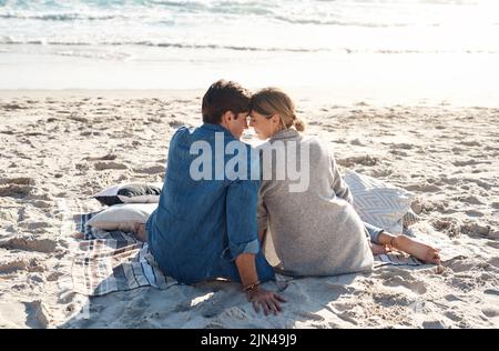 Das Leben am Strand ist anders. Rückansicht eines Paares mittleren Alters, das am Strand sitzt. Stockfoto