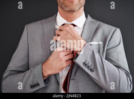 Hölle sei ein verheirateter Mann bis zum Ende von heute. Ein unkennbarer Bräutigam mittleren Alters justiert seine Krawatte in Vorbereitung auf seine Hochzeit. Stockfoto