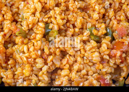 Traditioneller türkischer Bulgur-Pilaf mit Tomatensoße auf dem Teller (türkischer Name; Meyhane pilavi) Stockfoto