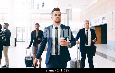 Bringen Sie das nächste große Arbeitsabenteuer mit: Drei Geschäftsleute, die tagsüber im Büro unterwegs sind und Koffer ziehen. Stockfoto