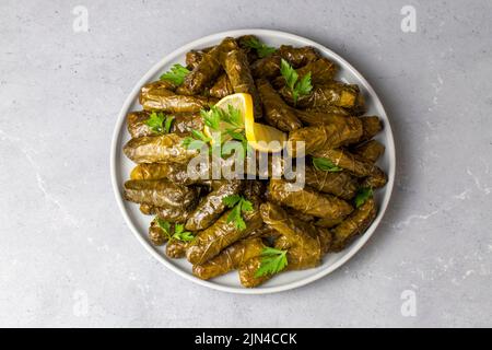 Köstliche Dolma (sarma) gefüllte Traubenblätter Reis, weiße Joghurt-Sauce. Libanesischer Dolma-Karma auf dem Teller. Libanon türkische griechische Küche aus dem Nahen Osten. (T Stockfoto