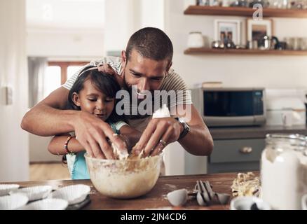 Die Welt, die wir entdeckt haben, liebt Sie nicht wie Ihre Familie Sie liebt. Ein Vater lehrt seine Tochter, wie man in der Küche zu Hause backen kann. Stockfoto