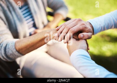 Sie können immer auf mich zählen. Eine unkenntliche Frau, die eine ältere Frau in den Händen hält. Stockfoto